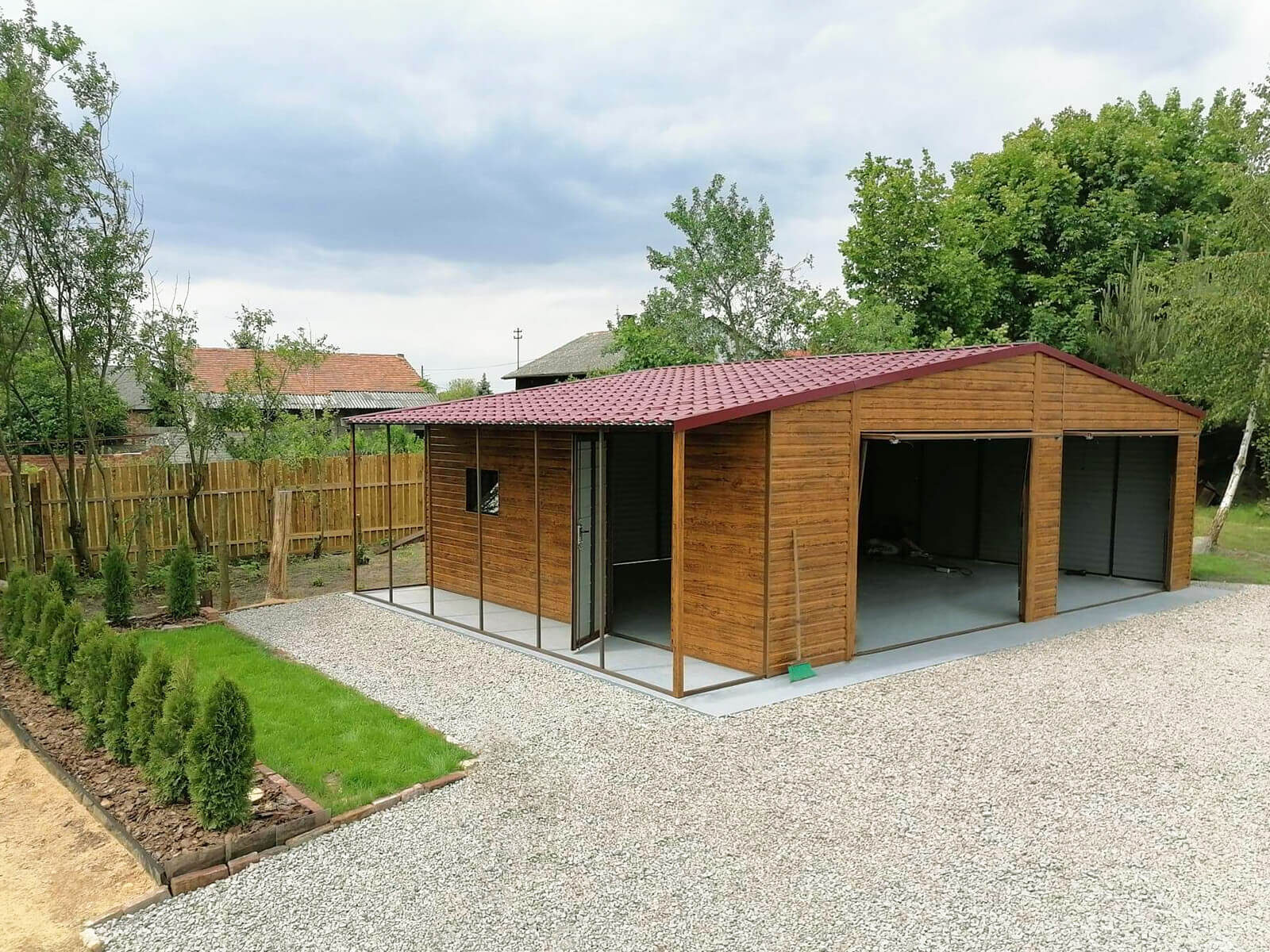 Garaż blaszany złoty dąb 8 x 6 + wiatka 1 x 6 dach dwuspadowy widok boczny z przodu, bramy podniesione, drzwi boczne otwarte, okno boczne uchylone