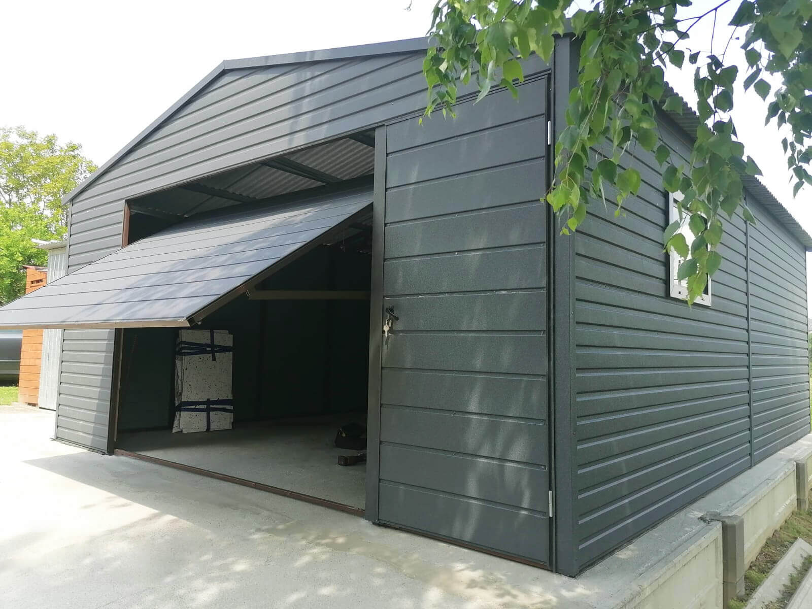 Garaż blaszany 5 x 6 Grafit Mat jednostanowiskowy, dwuspadowy, widok od frontu, brama uchylna podniesiona do połowy, drzwi przednie zamknięte